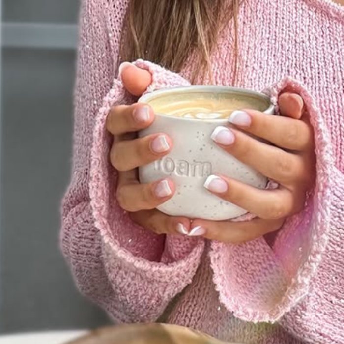 Ceașca foam cu latte art, ținută în mâini